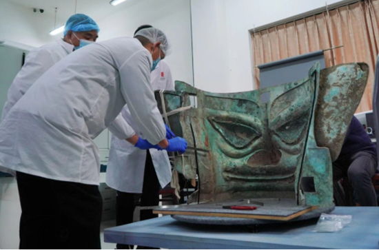 11月26日，文物修復師郭漢中(左二)帶領團隊為三星堆遺址3號坑出土的巨型青銅面具加固。